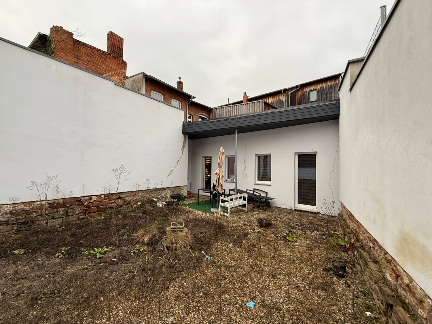 Originalaufnahme des umschlossenen Innenhofs mit weißen Wänden und niedrigem rückwärtigem Anbau